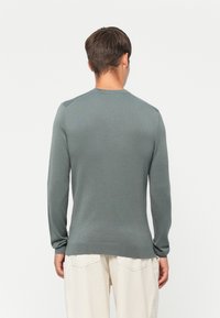 Gray, ribbed knit sweater with long sleeves and a rounded neckline, featuring a fitted design and a smooth texture.