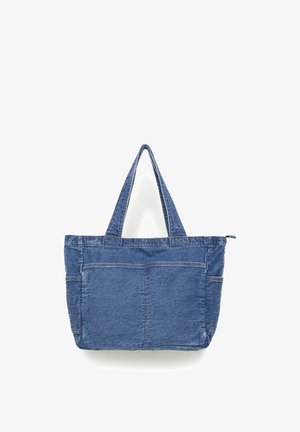 Blue denim tote bag with two handles, large front pocket, and side pockets, displayed against a white background.