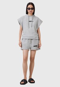 Sweat à capuche en coton gris à manches courtes avec cordons de serrage, associé à un short gris assorti avec poches latérales et un accent logo. Sandales noires.