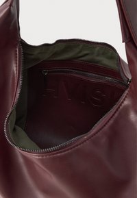 Avatud tumepunane nahkroog, mille sees on roheline kangas vooder ja lukuga sisetasku, millel on reljeefne "HVISK" bränd.