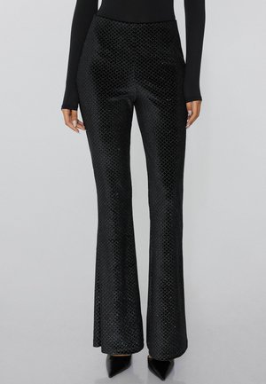 Black flared pants made of textured fabric with a sparkling diamond pattern. Features a high waist and slim fit down to the hem.