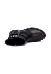 Botín negro hasta el tobillo con parte superior de cuero suave, panel lateral texturizado, acentos de doble hebilla y puntera redonda. El interior cuenta con forro suave.
