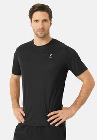 Černé sportovní tričko vyrobené z jemné, prodyšné tkaniny. Krátké rukávy, kulatý výstřih a decentní logo na hrudi. Texturovaný design.