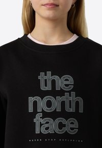 Μαύρο φούτερ από βαμβακερό μείγμα με μεγάλα λευκά γράμματα «the north face» και «NEVER STOP EXPLORING» από κάτω. Ριμπ γιακάς.