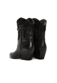Botas de vaquero de cuero negro con punta afilada, costuras decorativas y un tacón de madera apilada. Superficies texturizadas y un diseño elegante.