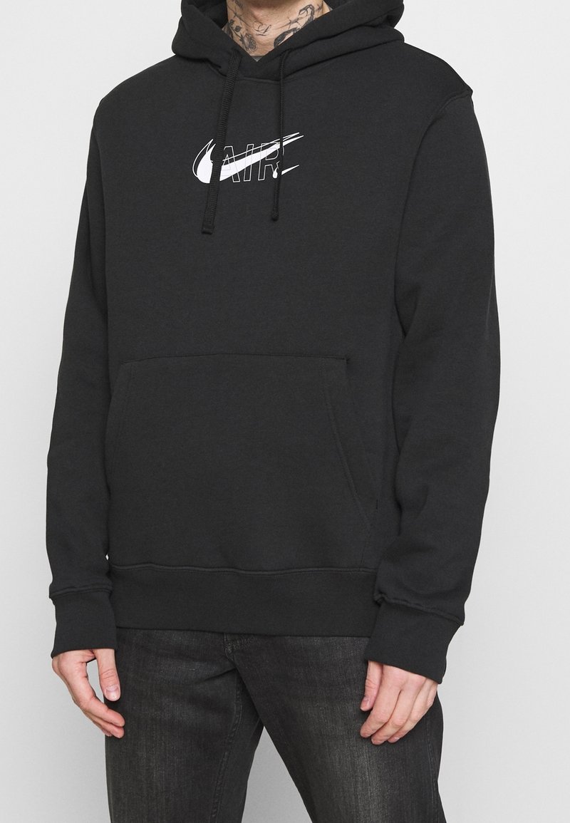 Černá mikina s kapucí vyrobená z bavlněné směsi, obsahující přední klokankovou kapsu a bílé logo Nike. Šňůrky na kapuci.