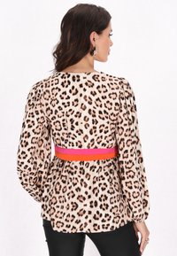 Luipaardprint blouse met lange mouwen, een riem met roze en oranje accenten, en een relaxte pasvorm. Glad stof met een lichte glans.