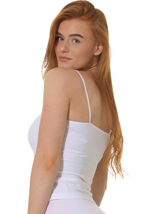 White fitted camisole with thin straps, showing a smooth cotton texture and a simple, classic design. Model poses with a slight turn.