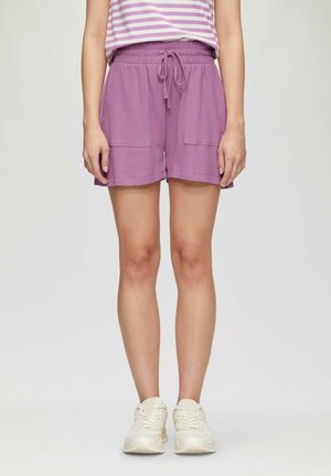 Lila, strukturierte Shorts mit einem elastischen Bund und Kordelzug, ausgestattet mit zwei Fronttaschen. Kombiniert mit weißen Sportschuhen.