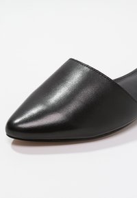 Spetsig tå svart lädersandaler med en slät yta, minimalistisk design och inga synliga detaljer eller accenter.