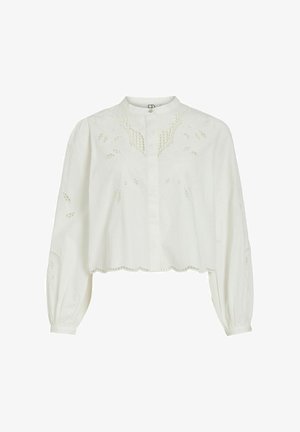 Vit kort blus med rund halsringning, långa ballongärmar, broderade detaljer och vågig kant. Tillverkad av lätt tyg.