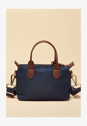 Tamsiai mėlyna rankinė su rudos odos rankenomis ir auksinės spalvos detalėmis, turi nuimamą petnešą ir užtraukiamą viršutinį uždarymą.