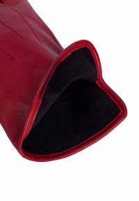 Czerwona skórzana rękawica z gładką powierzchnią, miękką czarną podszewką i lekko rozszerzanym mankietem. Szczegółowe przeszycia na powierzchni.