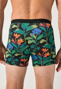 Černé boxerky s výrazným květinovým vzorem se zelenými listy, modrými květy a oranžovými akcenty. Měkký, pružný materiál a těsný střih.