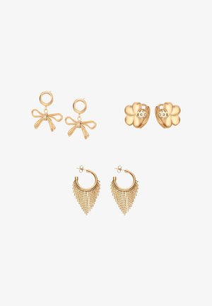 Drie paar gouden oorbellen: strikvormig met een ronde top, bloemenvormig met een strass-steen in het midden, en een creool met vallende gouden kettingen.