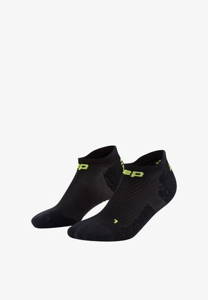 Schwarze Sportsocken mit einem niedrigen Schnitt, ausgestattet mit einer strukturierten Oberfläche und einem neongrünen Logo sowie Akzenten. Ideal für Sport und Freizeit.