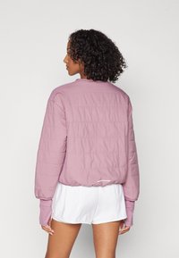 Let vatteret jakke i pastelfarvet pink med lange ærmer og en rundet kant. Den har et minimalistisk design og elastiske manchetter.