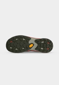Semelle d'une chaussure de randonnée avec une semelle extérieure en caoutchouc noir, des accents rouges et un logo Vibram jaune sur un fond gris clair.