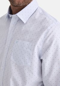 Hellblaues Button-Up-Hemd aus Baumwolle, mit schmalen vertikalen Streifen und kleinen dunkelblauen Punkten, sowie einer Brusttasche.