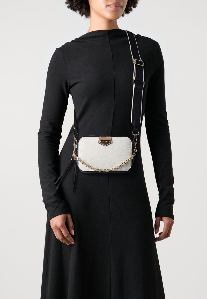 Biała skórzana torba na ramię z złotym łańcuszkiem, z fakturowanym wykończeniem i złotym akcentem metalowym.