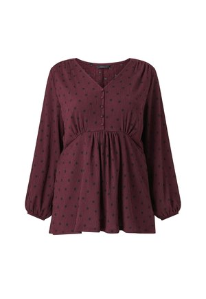 Bordeaux blouse met lange, bolle mouwen. Voorzien van een V-hals, knoopsluiting en zwart met witte stippenpatroon. Structuurstof met een geraffineerde taille.