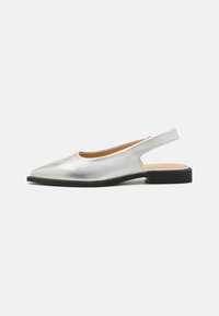 Ezüst színű slingback cipők hegyes orral, lapos fekete talppal és sima fényes felülettel. A kivágott sarok kialakítás növeli a légáteresztő képességet.