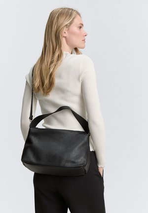 Borsa a spalla in pelle nera con finitura texturizzata, forma piatta, tracolla regolabile e chiusura con zip. Posizionata sulla schiena del modello.