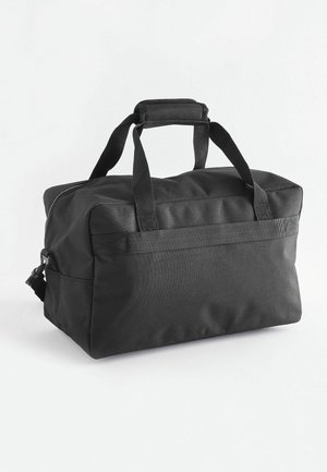 Sac de voyage en tissu noir avec deux poignées supérieures, fermeture éclair et une bandoulière détachable. Il présente une forme rectangulaire et une texture lisse.