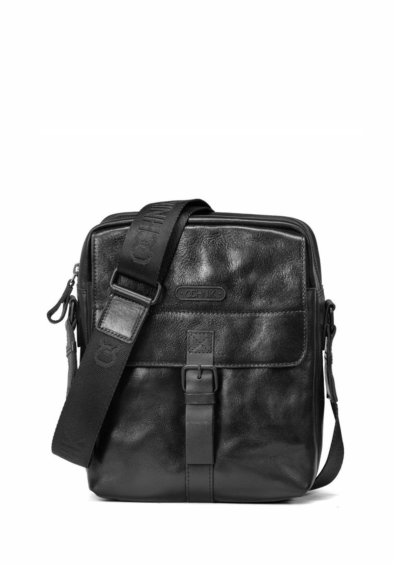 Czarna skórzana torba na ramię o fakturowanym wykończeniu, regulowanym pasku, przedniej klapie z klamrą i detalem z logo. Kompaktowy prostokątny kształt.