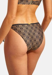 Zwarte bikini onderkant met een geometrisch gouden patroon. Heeft een middelhoge snit en soepel materiaal. Bevat een decoratief logo aan de achterkant.