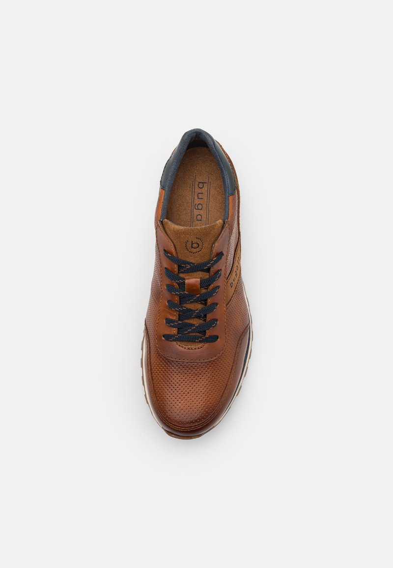 Chaussure en cuir marron avec un design perforé, accents bleu marine, lacets noirs et une semelle rembourrée. Logo de la marque visible sur la semelle intérieure.