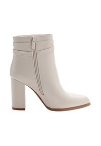 Krämfärgade kvinnors ankelstövlar med blockklack, sidodragkedja och dekorativa horisontella remmar runt ankeln.
