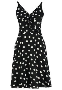 Robe noire sans manches à pois blancs, col en V, détail volanté sur la poitrine et jupe évasée longueur genou.