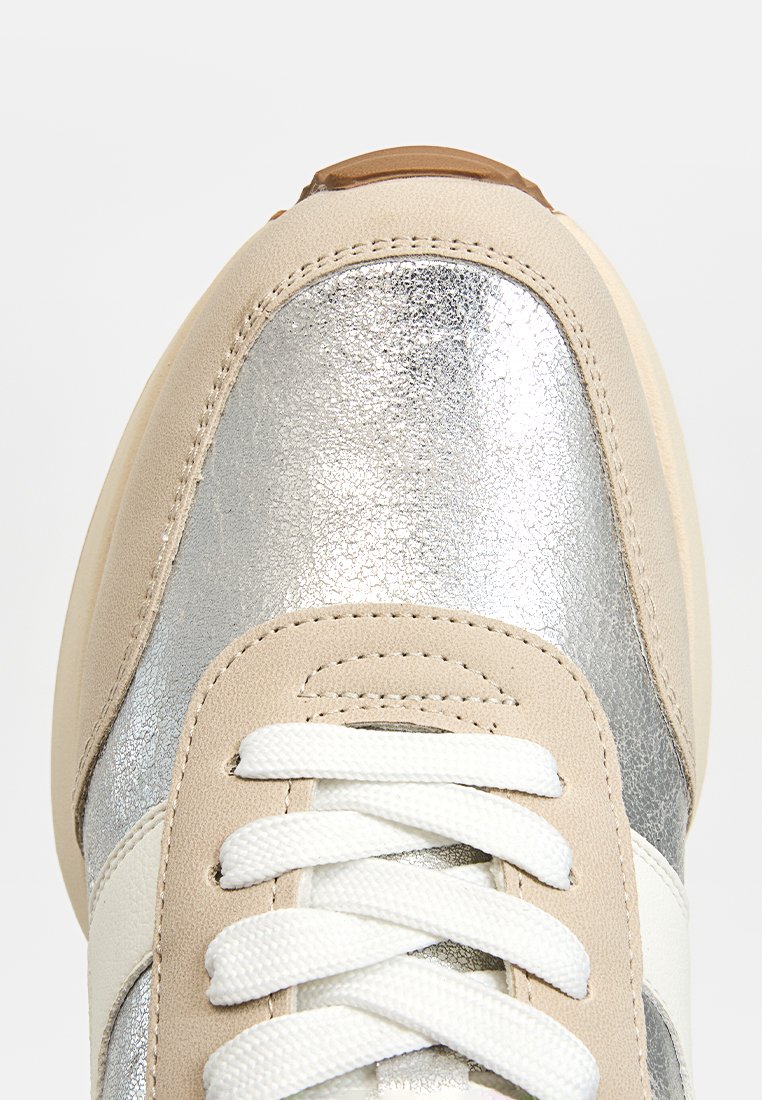 Sneaker con punta in metallo argento, lati in suede beige, lacci bianchi e suola in gomma marrone chiaro. Texture liscia e design atletico classico.