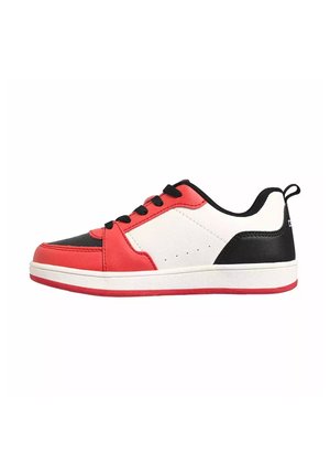 Zapatilla baja en rojo, blanco y negro con cordones negros, media suela blanca y suela exterior roja sobre fondo blanco liso.
