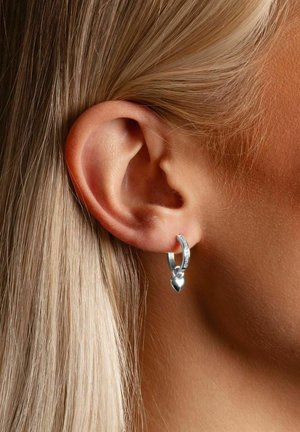 Silver hoop earrings with a heart pendant, featuring a textured surface and small sparkling accents, worn on an ear close-up.