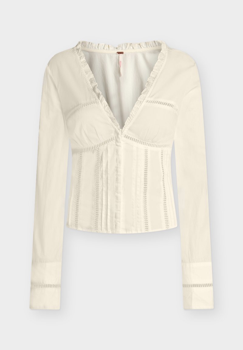 Κρεμ μπλούζα με μακριά μανίκια, βαθύ V-λαιμόκοψη, λεπτή διακόσμηση με βολάν, κάθετες τρύπες και εφαρμοστή μέση.