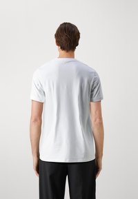 Vit t-shirt med kort ärm i mjuk bomull, med rund halsringning och en minimalistisk design utan synliga mönster eller grafik.