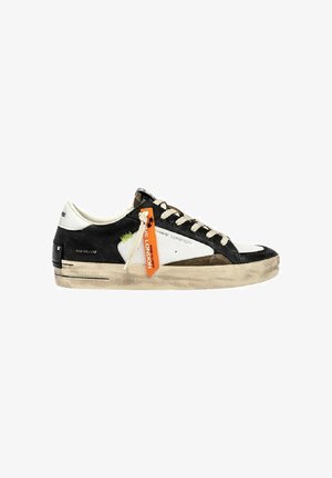 Sneaker nera e bianca a basso profilo con suola beige, lacci beige, cuciture verdi e un'etichetta arancione con scritto "Sk8 De Luxe."
