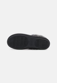 Svart gummiyttersula med texturerade spår, med en lätt kurva och en subtil logotypprägling. Mjuk grått övre material är inte synligt.