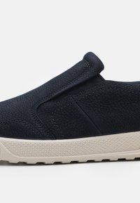 Marinefarbene Slipper aus strukturiertem Leder mit elastischen Seitenpaneelen und einer beigen Gummisohle, die ein Rautenmuster für besseren Halt aufweist.
