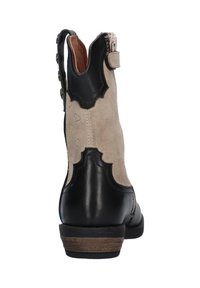 Stivaletto in pelle nera e camoscio beige con design scallop, zip sul retro e tacco basso. Presenta un motivo a cuori sul lato in camoscio.