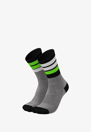 Graue Socken mit einer schwarzen Zehenpartie, die auf dem Einkaufsbereich horizontale Streifen in Schwarz, Weiß und Grün aufweisen. Aus einem glatten, dehnbaren Material gefertigt.
