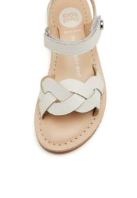 Sandalo in pelle bianca con design a fascia intrecciata, apertura per le dita e cinturino alla caviglia regolabile. Soletta di colore naturale con dettagli cuciti.