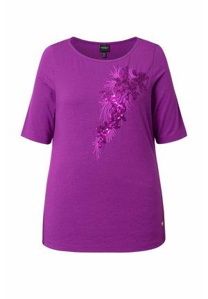 Chemise violette à manches courtes avec encolure ronde et motif floral diagonal en sequins sur la poitrine, ourlet uni et coupe décontractée.