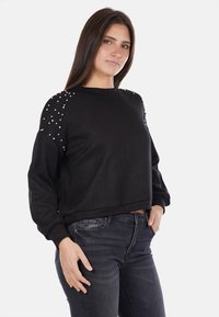 Felpa nera con vestibilità rilassata, scollatura rotonda e dettagli decorativi in perle sulle spalle. Realizzata in tessuto morbido.