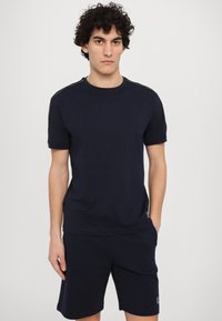 T-shirt de algodão azul marinho com mangas curtas, decote redondo e detalhes nos ombros; combinado com calções azul marinho a condizer com detalhe de logótipo.