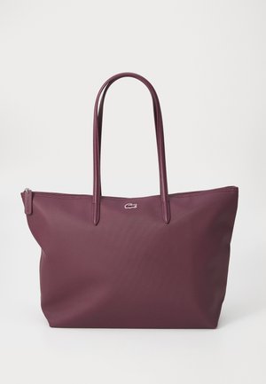 Sac fourre-tout de couleur bourgogne profonde, fabriqué en matériau texturé. Dispose de deux poignées allongées et d'un logo discret à l'avant. Fermeture zippée.