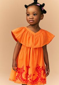 Oranje katoenen jurk met een flared ruffles halslijn, geborduurde rode bloemenpatronen op de rok en textuurstof.
