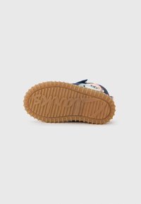Gummisåle på sneakers, med en teksturert tan yttersåle med logo. Mørkeblå overdel med fargerik trykt design og stofflapp.